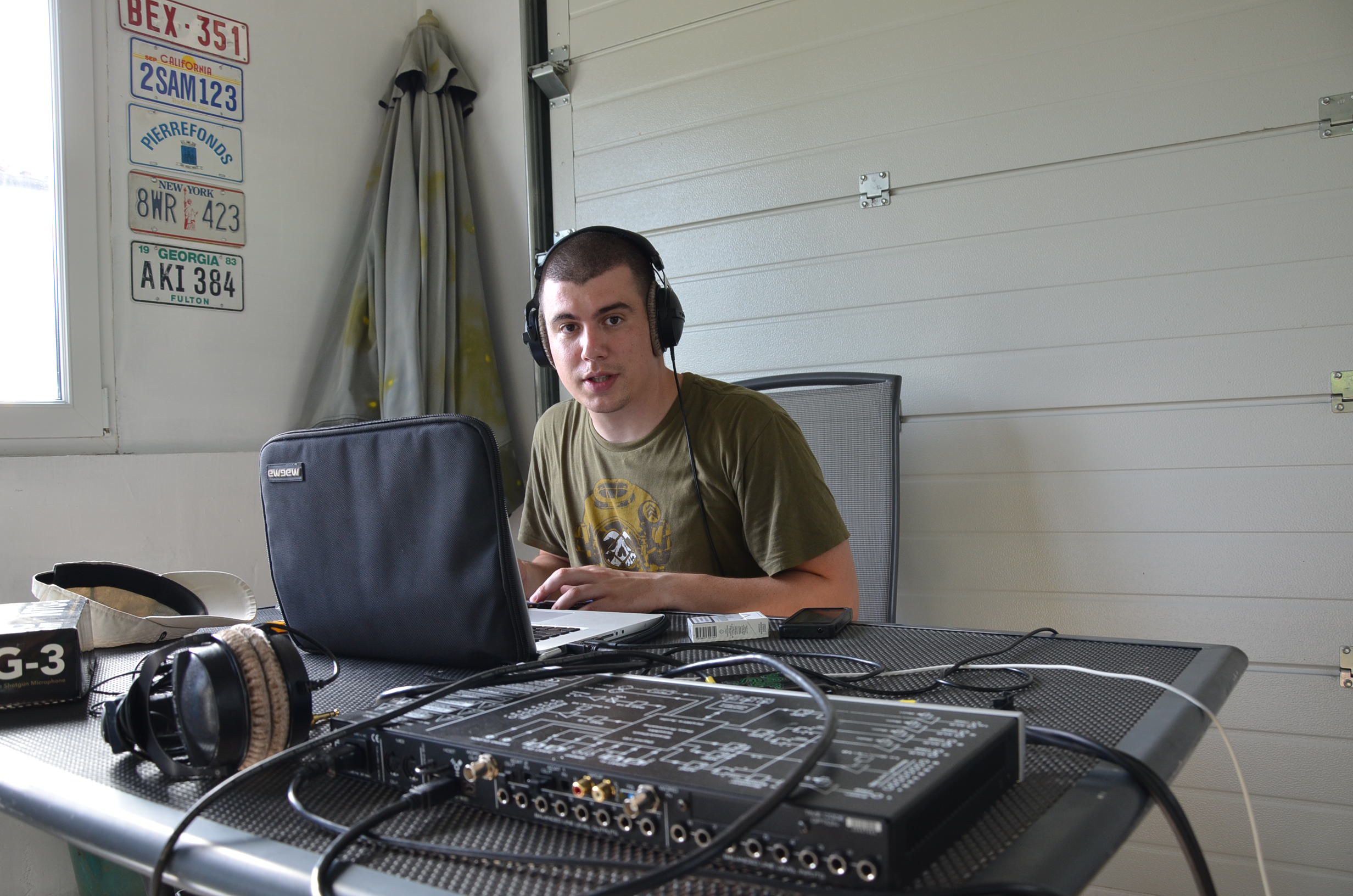 Daniel sitting at the working desk in a garage with a laptop and sound interfce in front of him.